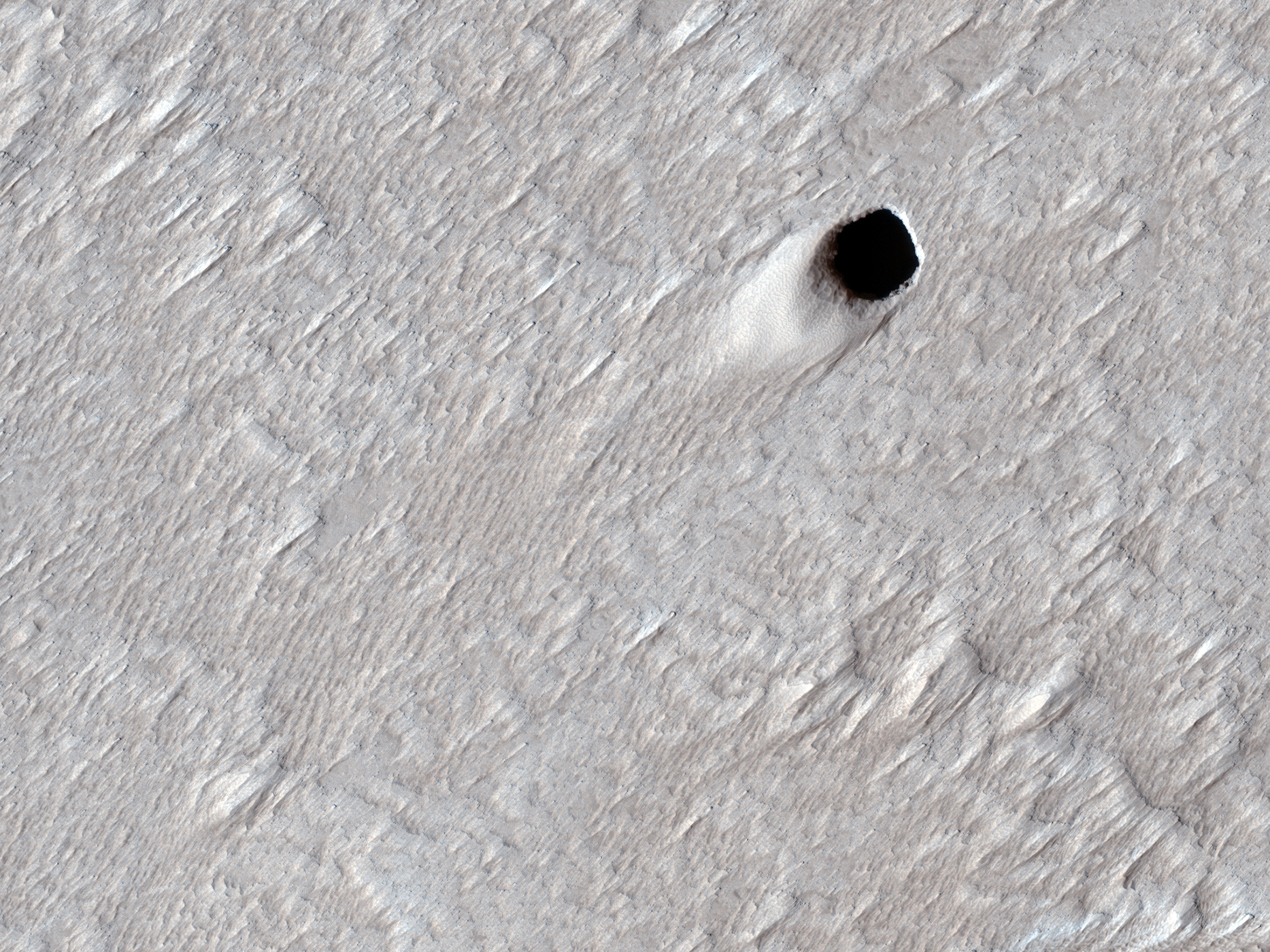 This pit crater was created by an empty lava tube in Mars’ Arsia Mons region. The image was captured by NASA’s Mars Reconnaissance Orbiter on Aug. 16, 2020.