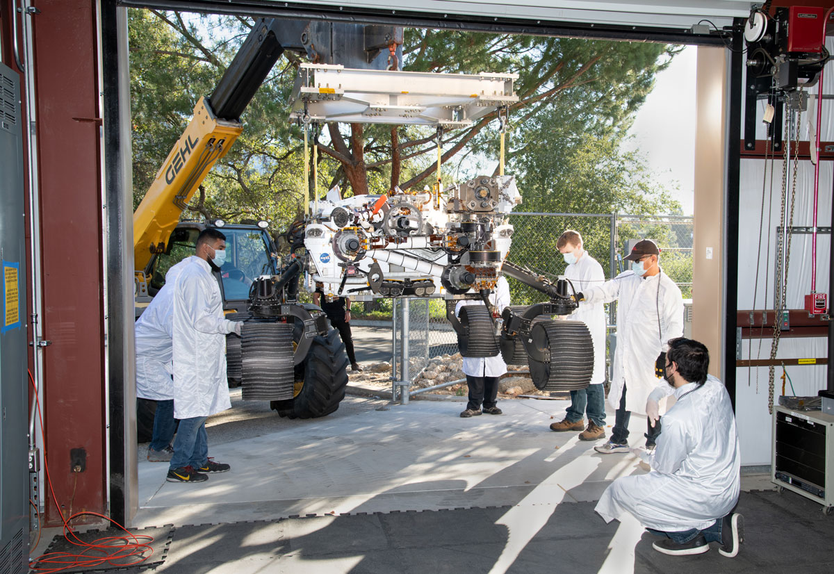 On Oct. 29, 2021, a heavy-duty vehicle transports the Perseverance rover’s engineering model, called OPTIMISM, from a test lab to the Mars Yard garage at JPL.