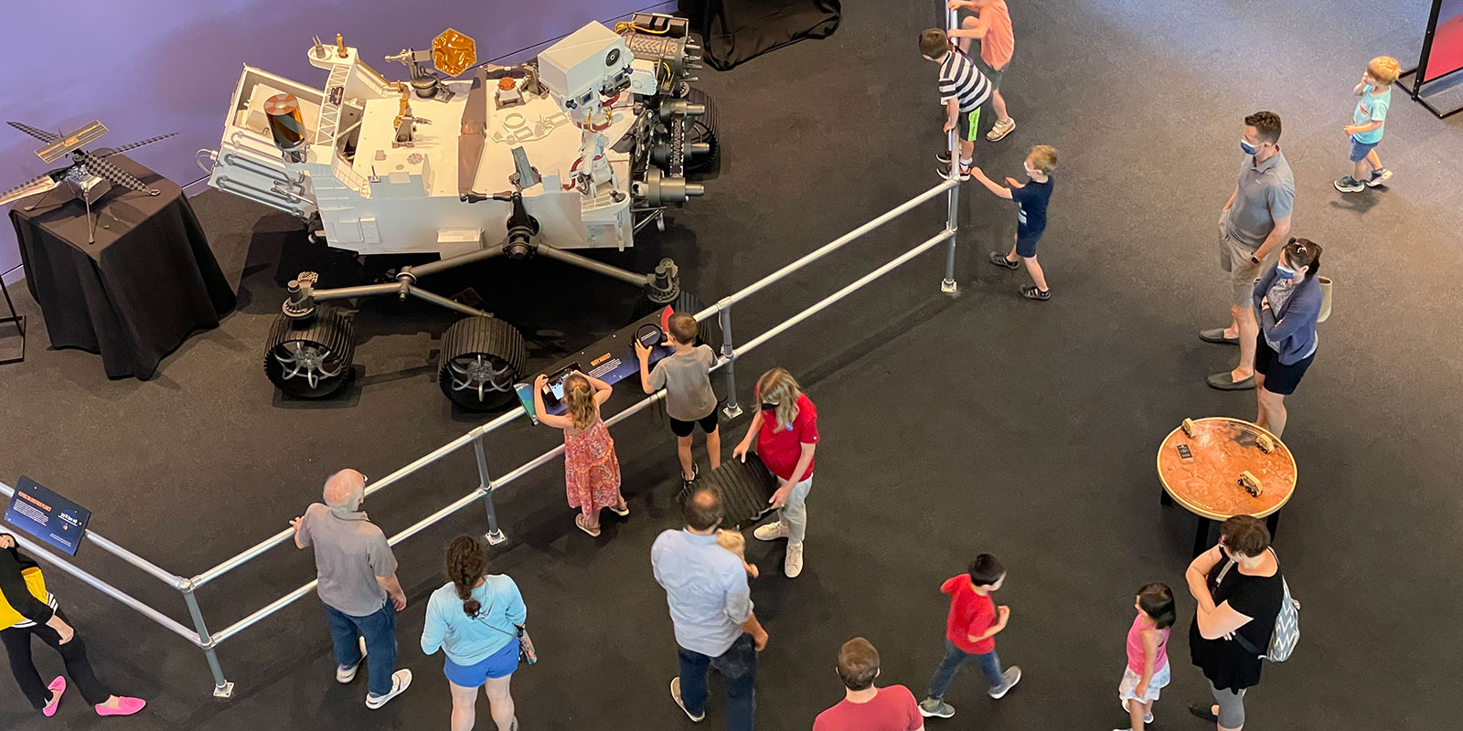 Overhead view of members of the public looking at a life-size model of NASA's Perseverance rover at the Science Center of Iowa.
