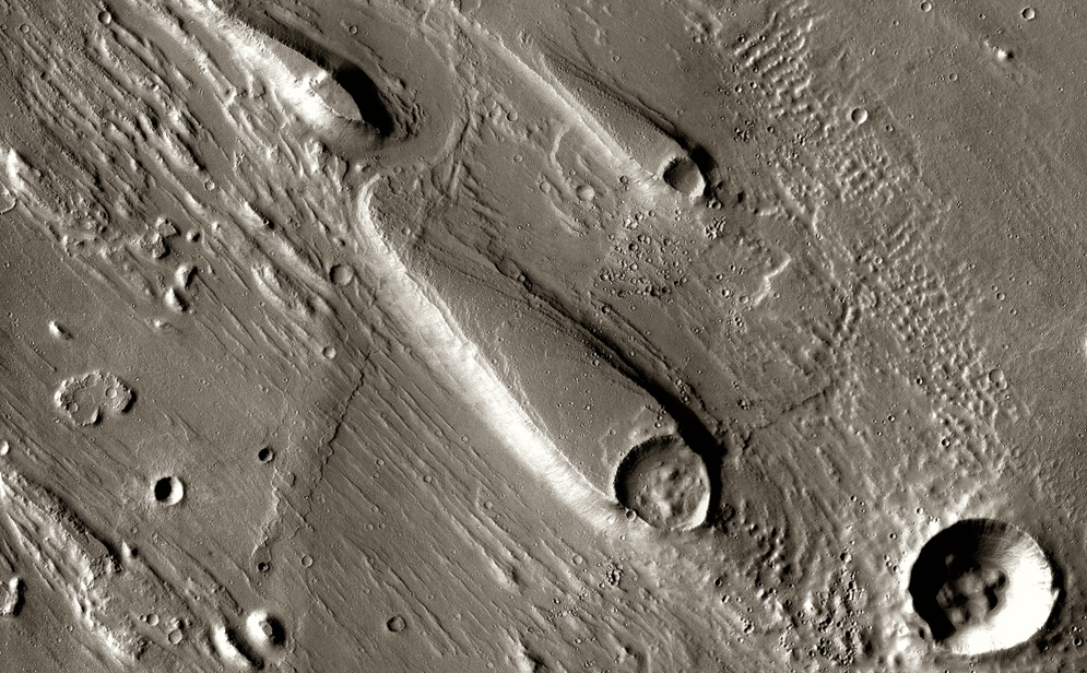 In Ares Vallis, teardrop mesas extend like pennants behind impact craters, where the raised rocky rims diverted the floods and protected the ground from erosion.