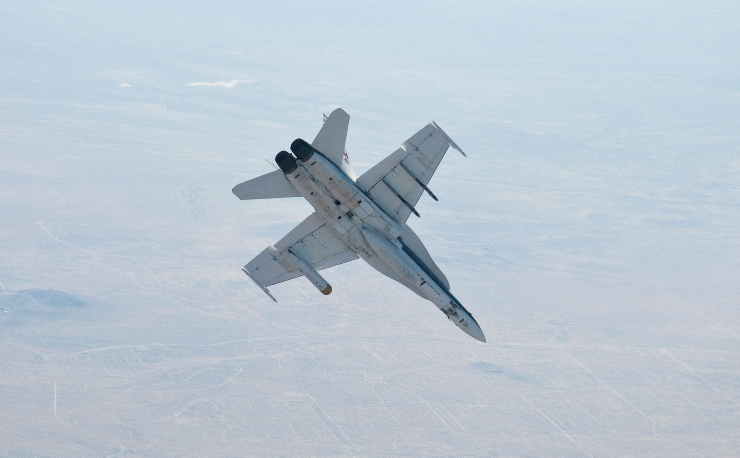 A NASA Dryden Flight Research Center F/A-18 852 aircraft performs a roll during a dive toward Rogers Dry Lake at Edwards Air Force Base, Calif., during June 2011 flight tests of a Mars landing radar.