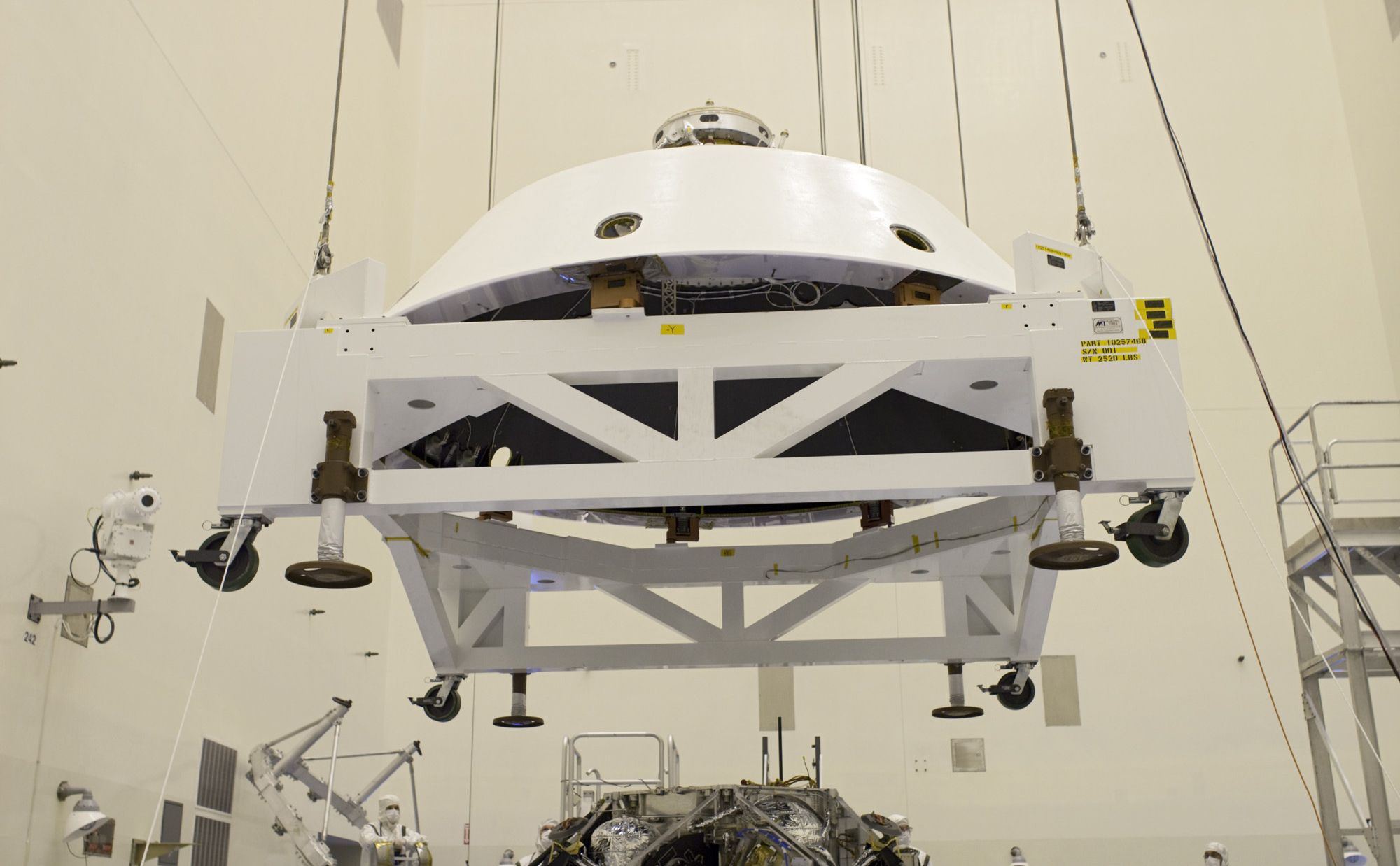 In the Payload Hazardous Servicing Facility at NASA's Kennedy Space Center in Florida, technicians guide the backshell as it is lowered over NASA's Mars Science Laboratory (MSL) rover, Curiosity, for encapsulation.