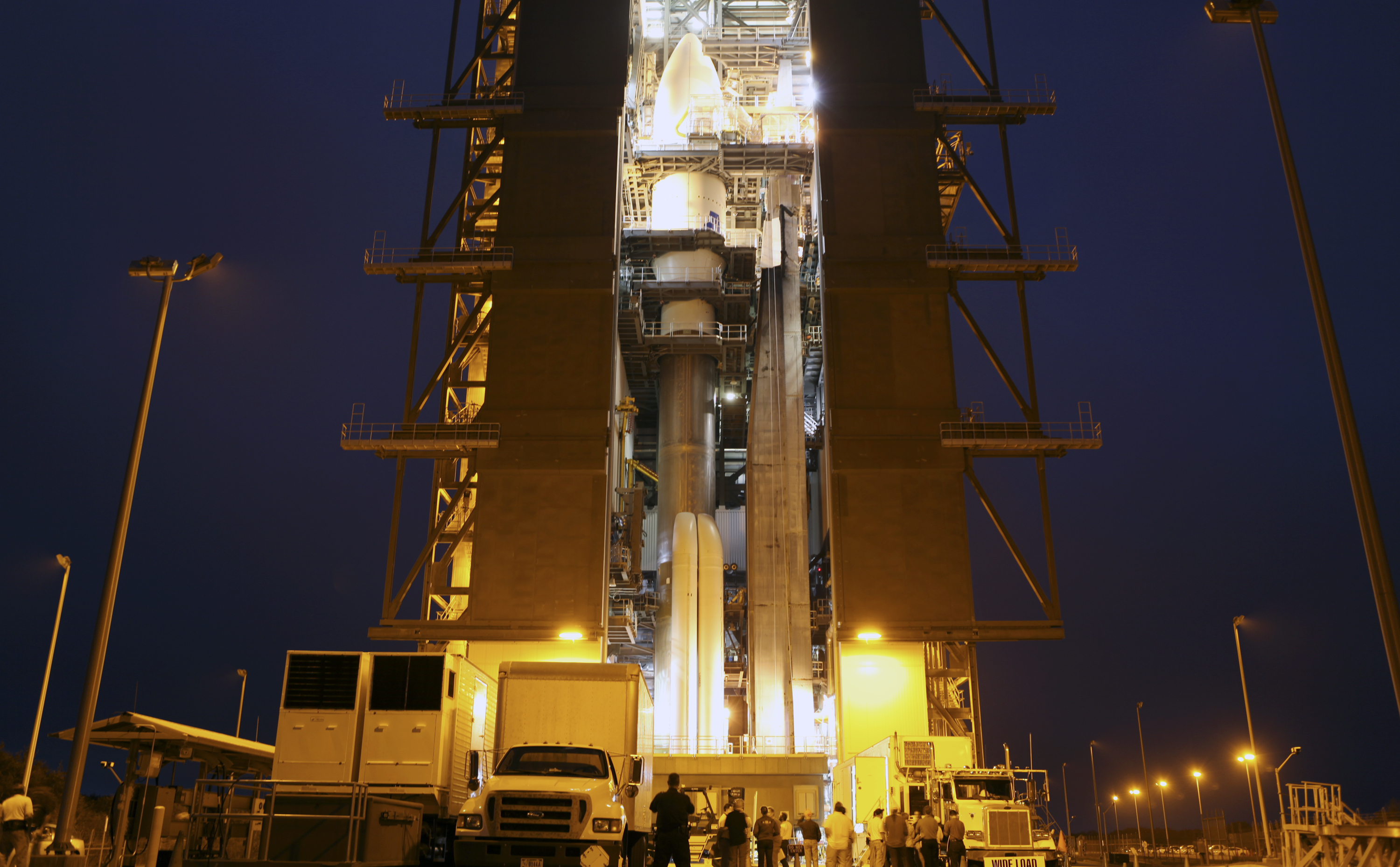 The Atlas V rocket set to launch NASA's Mars Science Laboratory (MSL) mission is illuminated inside the Vertical Integration Facility at Space Launch Complex 41, where employees have gathered to hoist the spacecraft's multi-mission radioisotope thermoelectric generator (MMRTG).