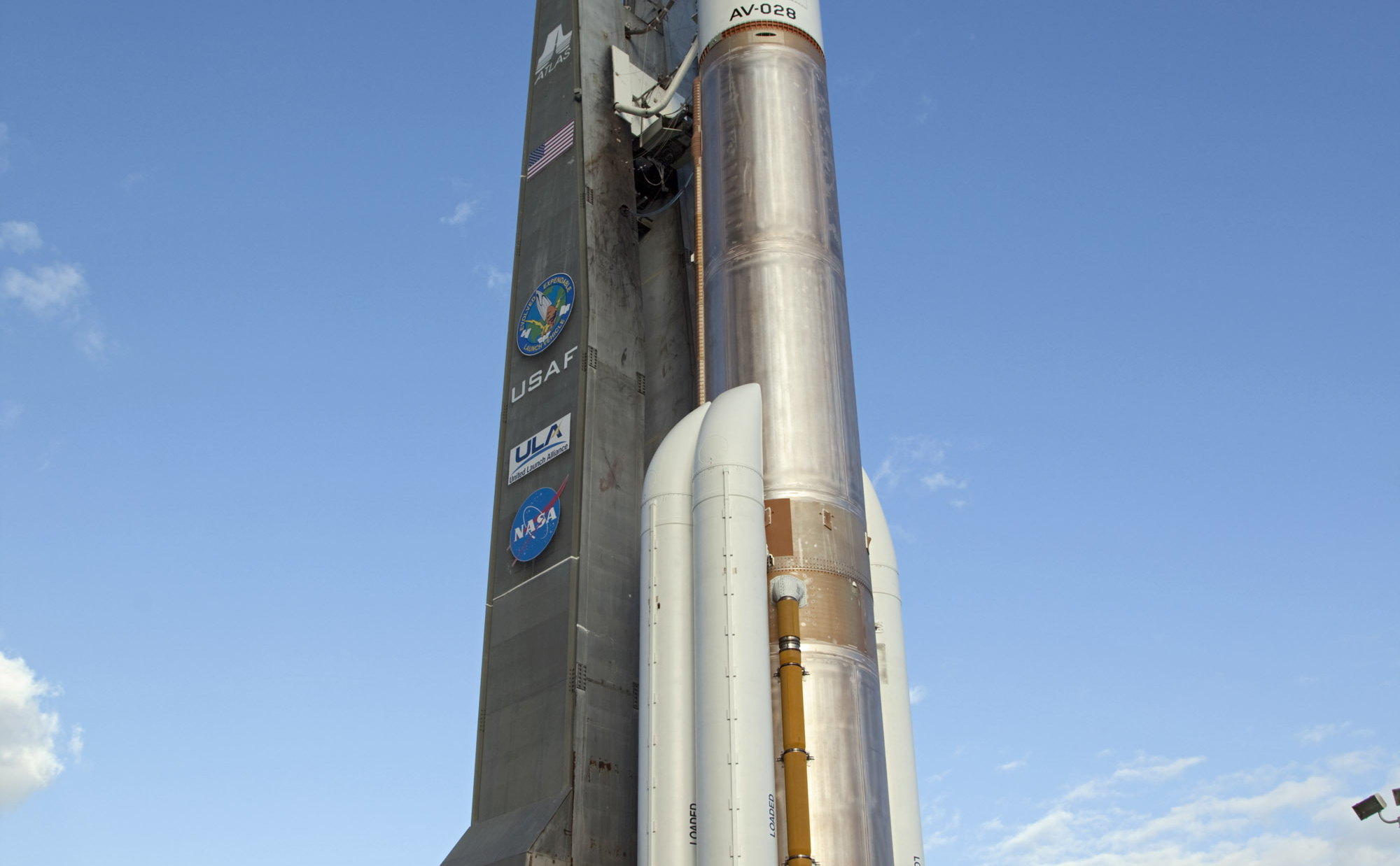 On Cape Canaveral Air Force Station in Florida, the 197-foot-tall United Launch Alliance Atlas V rocket is backdropped by a bright blue sky as the vehicle rolls from the Vertical Integration Facility (VIF) to the launch pad at Space Launch Complex 41.