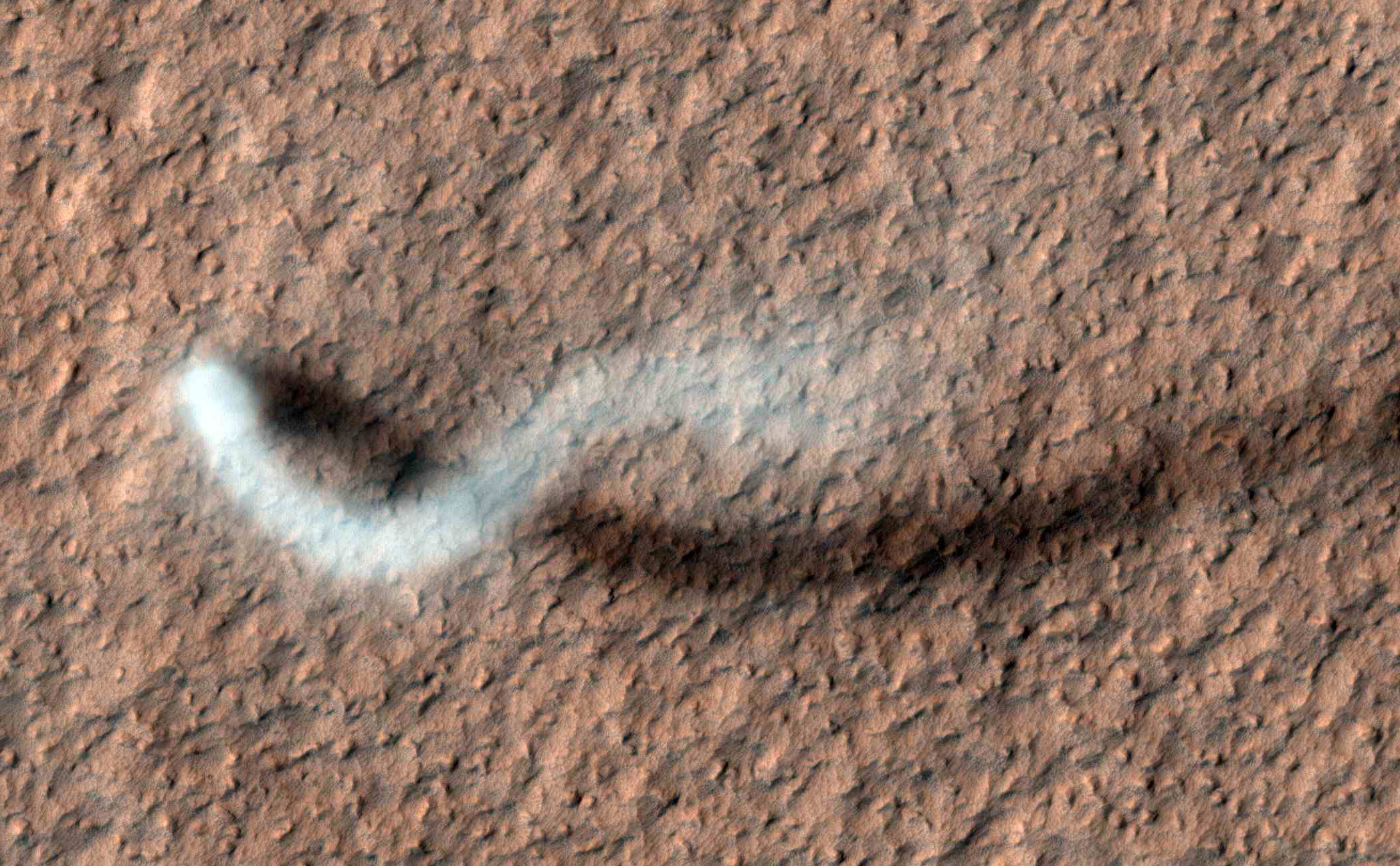 A towering dust devil, casts a serpentine shadow over the Martian surface in this image acquired by the High Resolution Imaging Science Experiment (HiRISE) camera on NASA's Mars Reconnaissance Orbiter.