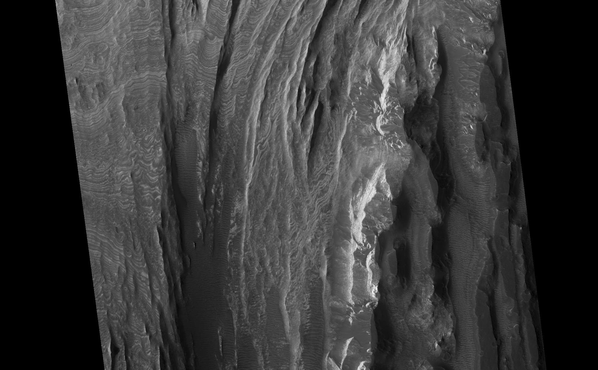 This HiRISE image shows a portion of interior layered deposits (ILD) in Juventae Chasma. Juventae Chasma is a large depression near the equatorial canyon system Valles Marineris. The scene is along the top of a mound of layered deposits on the floor of Juventae Chasma. Dunes are seen in the low-lying, darker regions. Very fine layers are also seen (see subimage, approximately 1 km across). Understanding what kinds of materials formed the layers, how they were set in place, and how they have evolved will provide insight into Martian geologic history.