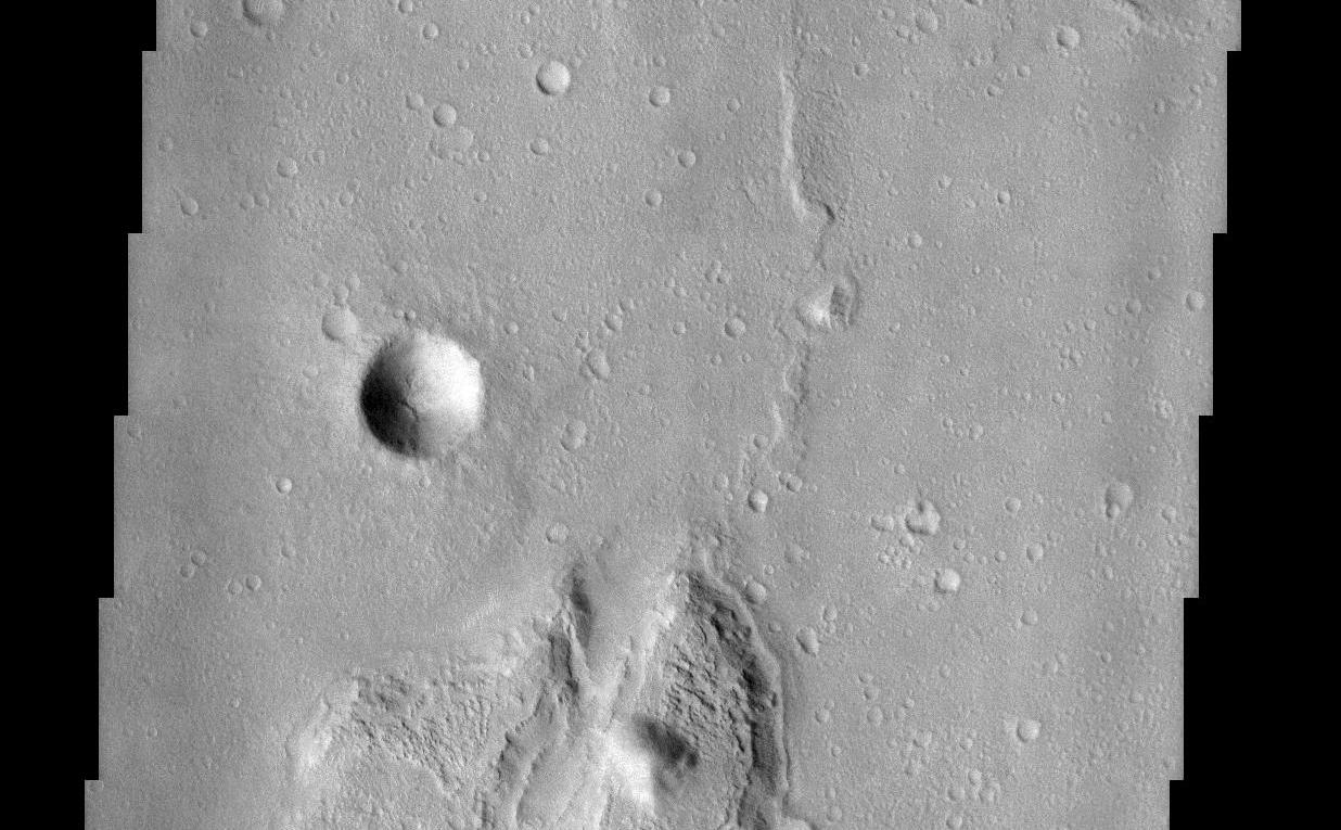 This lunar-like scene occurs along the southeastern rim of the Isidis Planitia basin. The Isidis basin is an ancient impact crater some 1200 km across that is found along the boundary separating the heavily-cratered southern highland terrain of Mars from the northern lowlands. Elements of both terrains are evident in this image as an island of rugged highland terrain surrounded by smoother lowland terrain. The resurfacing of the Isidis basin produced a system of wrinkle ridges, some of which are seen on the lowland terrain in the image. Wrinkle ridges are a common feature on the surface of the moon and add to the lunar-like quality of this image. Layers are visible in the large island, the most resistant of which likely are from lava flows that created the highland terrain. The process by which the global-scale highland/lowland dichotomy was created remains a mystery.