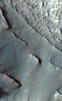 This image shows part of the floor of an impact crater on the northern rim of the giant Hellas Basin. Hellas includes the lowest elevations on Mars, and may have once held lakes or seas; layered rock outcrops occur around much of the edge of the basin. At this site, a large impact crater (about 90 kilometers across) was partly filled by layered rocks. These rocks on the crater floor are now eroding and forming strange pits.Here, the layers are mostly exposed on a steep slope which cuts across much of the image. On this slope, they crop out as rocky stripes, some continuous and others not. The material between the stripes is mostly covered by debris, but some areas of exposed rock are visible. The slope is capped by a thick, continuous layer that armors it against erosion; once this cap is gone, the lower material is removed rapidly, forming the steep slope. At the base of this slope, rocks on the floor of the pit appear bright and heavily fragmented by cracks known as joints.The variation in rock types suggests that the rocks here were deposited by multiple processes or in different environments. Sites like this may preserve a record of conditions on early Mars.