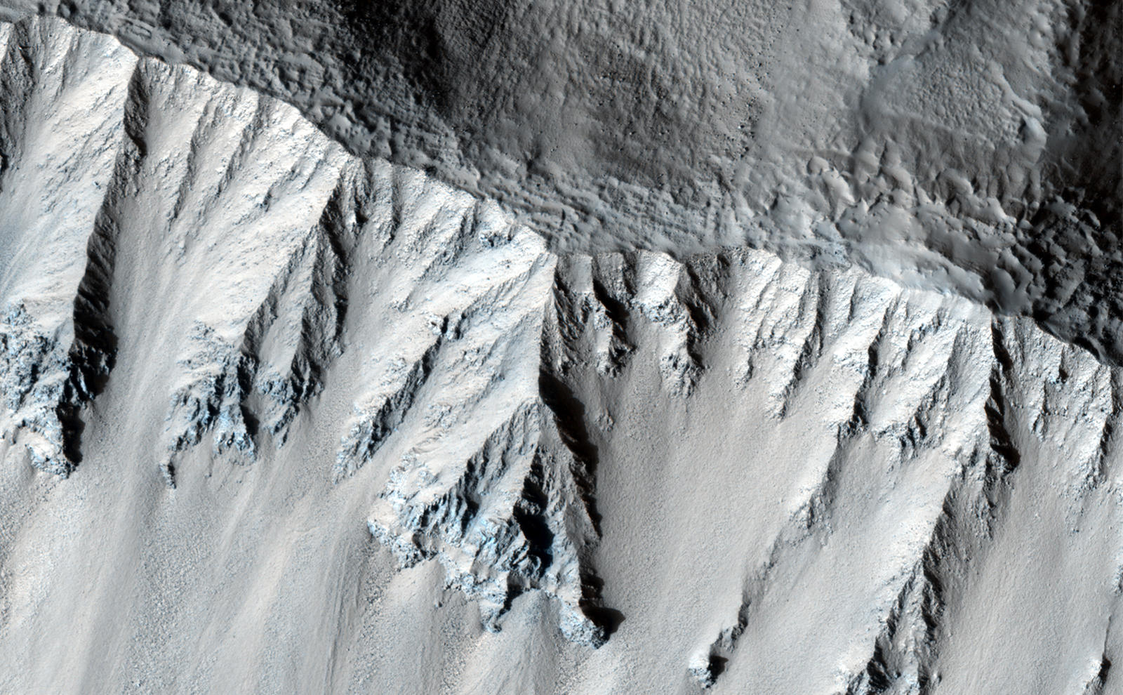 This fresh crater is located in the northern mid-latitudes. It is designated as fresh because of its very sharp rim.The crater has experienced some modification since it formed, including a few tiny craters on the south wall.The rough texture of the floor is suggestive of ground ice, which is expected to exist in the mid-latitudes. Ground ice aids gravity in moving material from the crater walls towards the center. Material is visible slumping off the northwest crater wall in this fashion. The wavy texture of the center of the crater floor suggests that material has been transported from the walls and merged in the center.