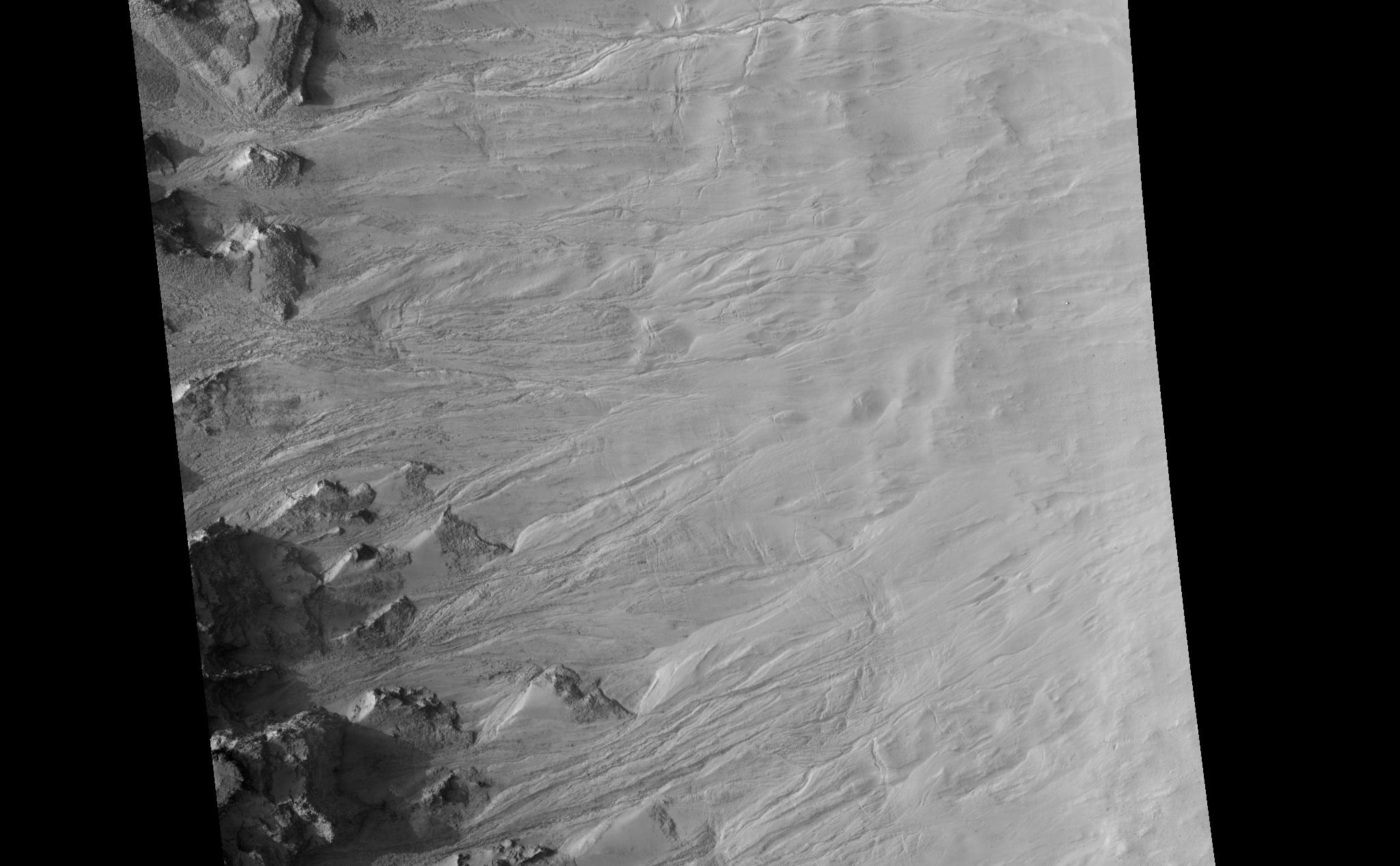 Geologically young gullies are a prime target for the HiRISE camera. Gullies are located in a variety of settings and are found all over Mars.This "ring trough" or eroded pit crater, is located in the rugged southern highland terrain known as Noachis Terra. The HiRISE image shows the layered, boulder-rich wall rock facing to the northeast and gullies that are transporting material downslope.The material collects into debris aprons along the walls, which often exhibit narrow channels along its surface.