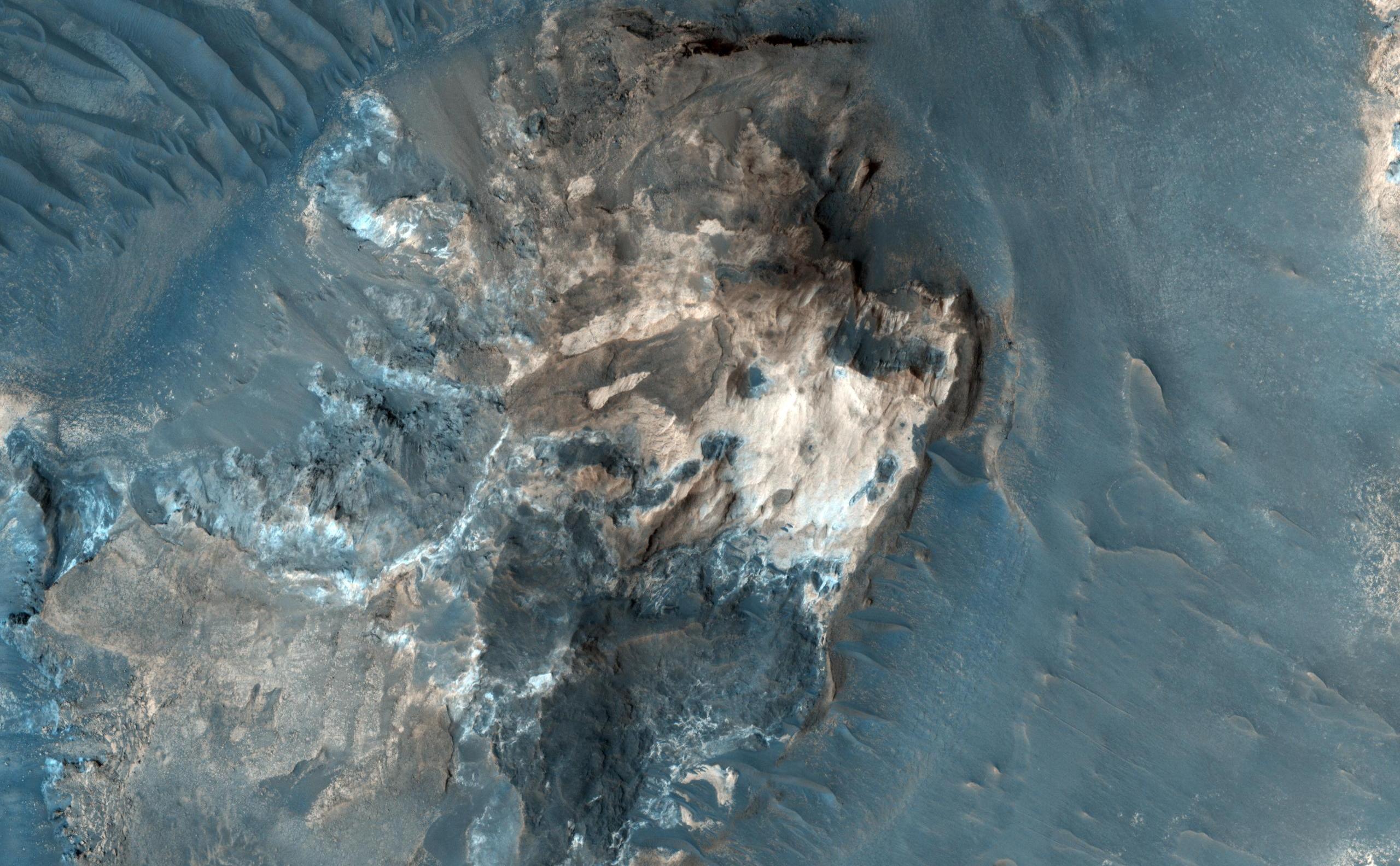 The formation of the large outflow channels on Mars have been attributed to catastrophic discharges of ground water. Many of the channels start in areas where the ground has apparently collapsed: the surface is now well below the surrounding undisturbed ground. Within the collapsed region, blocks of undisturbed material can often be seen and this has led to such regions being called chaotic terrain.In Aureum Chaos, the OMEGA experiment on Mars Express indicated the presence of phyllosilicates (clay minerals) which have been detected in a variety of bright outcrops and scarps. The subimage shows such an outcrop in a chaotic terrain region. At the highest resolution, layering can be seen. The image will be used to assess at what stage in Mars's history these clays minerals were formed and how.The area referred to as Aureum Chaos is located at 334 degrees East, 4 degrees South on the West side of the Margaritifer Terra region of Mars.