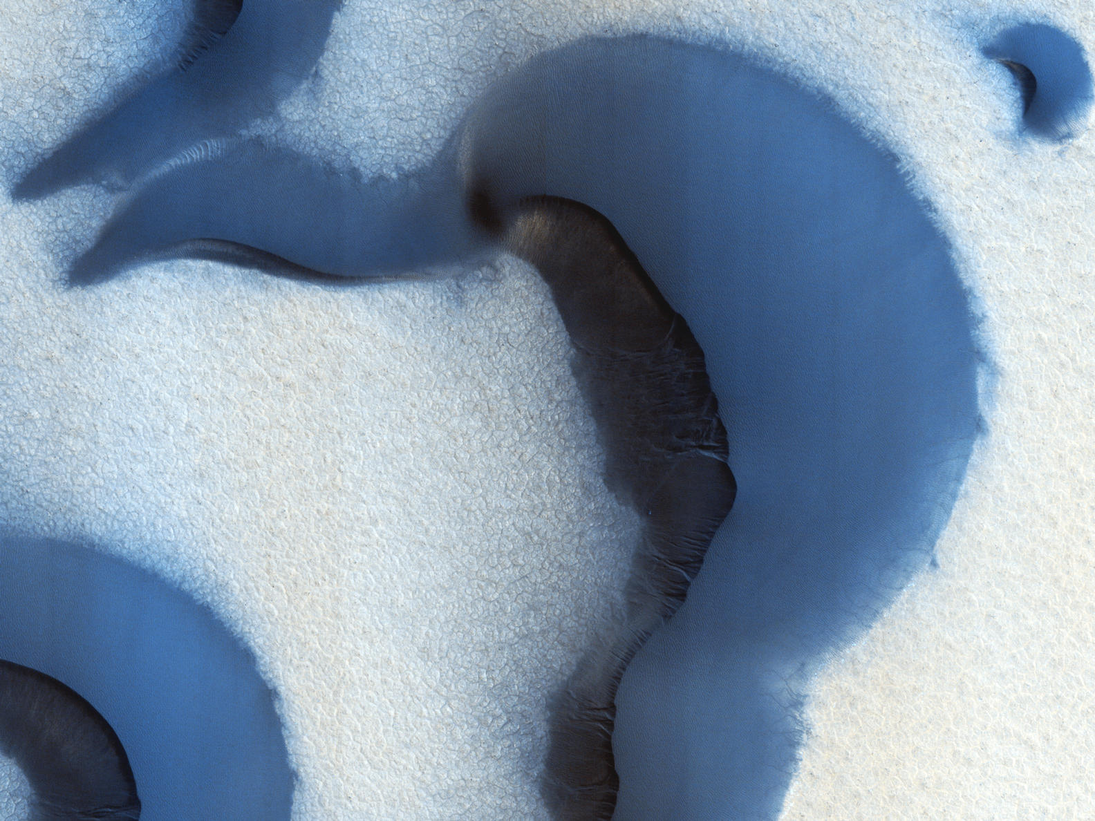 This picture was taken during the Martian summer with only small patches of ice remaining at the surface; they show up as bright, somewhat blue, spots on slopes that provide some shading from the Sun.
