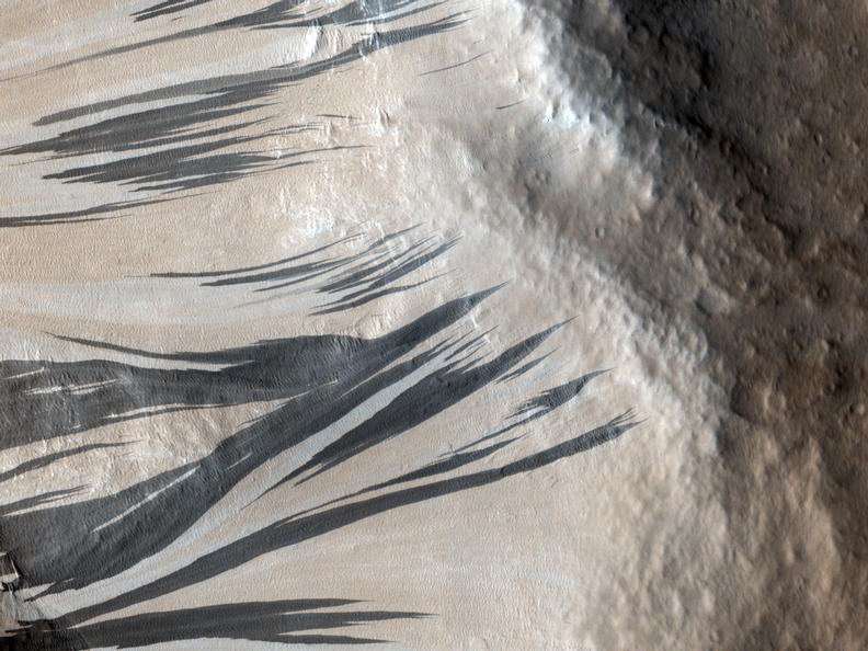 This observation shows a portion of the wall (light-toned material) and floor of a trough in the Acheron Fossae region of Mars. Many dark and light-toned slope streaks are visible on the wall of the trough surrounded by dunes.