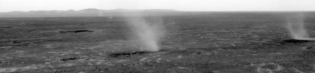 This image hows several dust devils moving from right to left across a plain inside Mars' Gusev Crater, as seen from the vantage point of NASA's Mars Exploration Rover Spirit in hills rising from the plain.