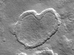 Mars Global Surveyor (MGS) Mars Orbiter Camera (MOC) took this image in April 2004.  This heart-shaped featureis a depression which occurs a low mesa located near 57.5°N, 135.0°W, and is about 1 km (~0.62 mi) wide.