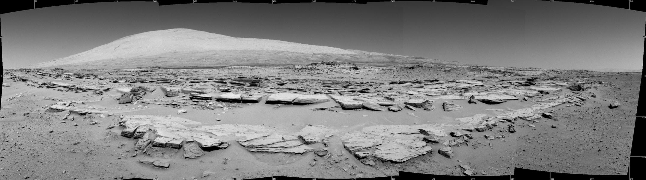 A landscape scene from NASA's Curiosity Mars rover shows rock rows at "Junda" forming striations in the foreground, with Mount Sharp on the horizon. The component images were taken by the rover's Navigation Camera (Navcam), looking southward, during a pause in driving on Feb. 19.