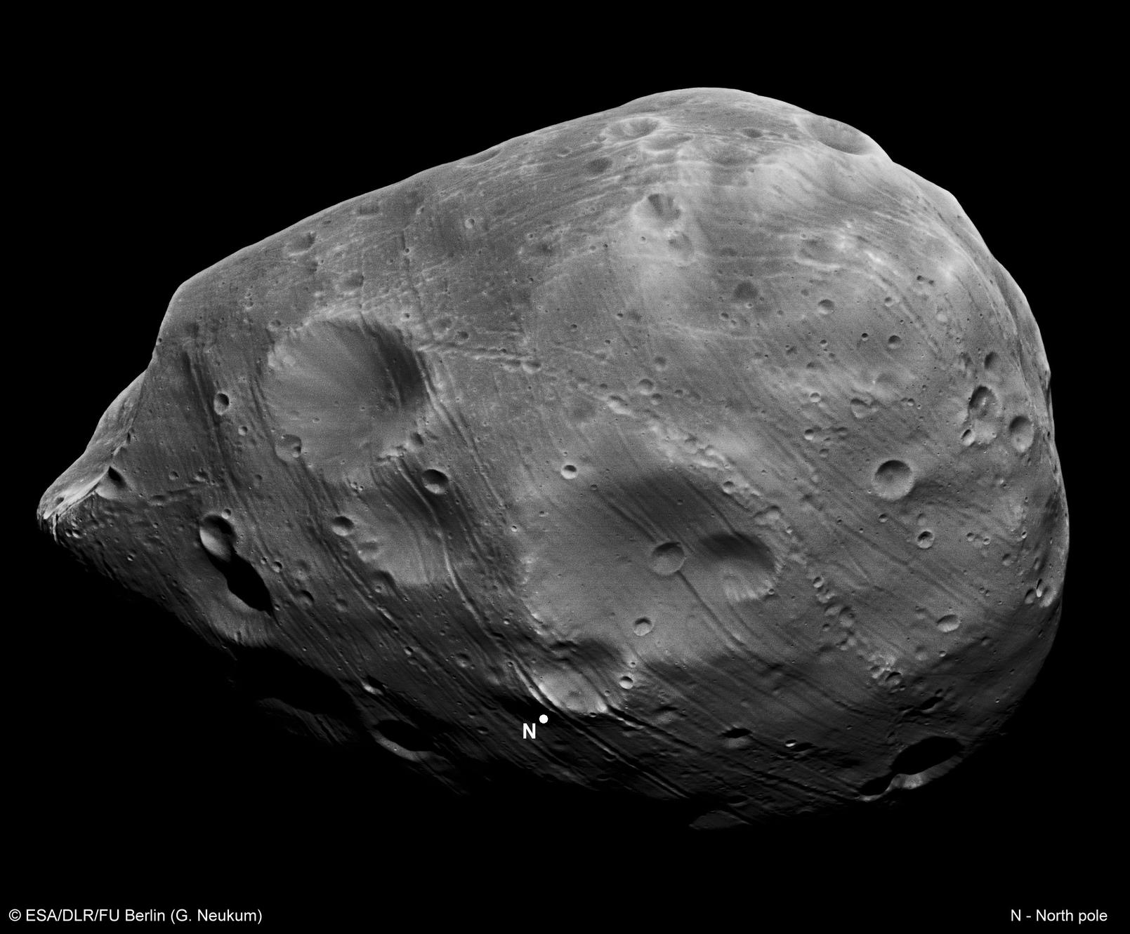 Visible in great detail is Phobos' irregular shape, strangely dark terrain, numerous unusual grooves, and a spectacular chain of craters crossing the image center.