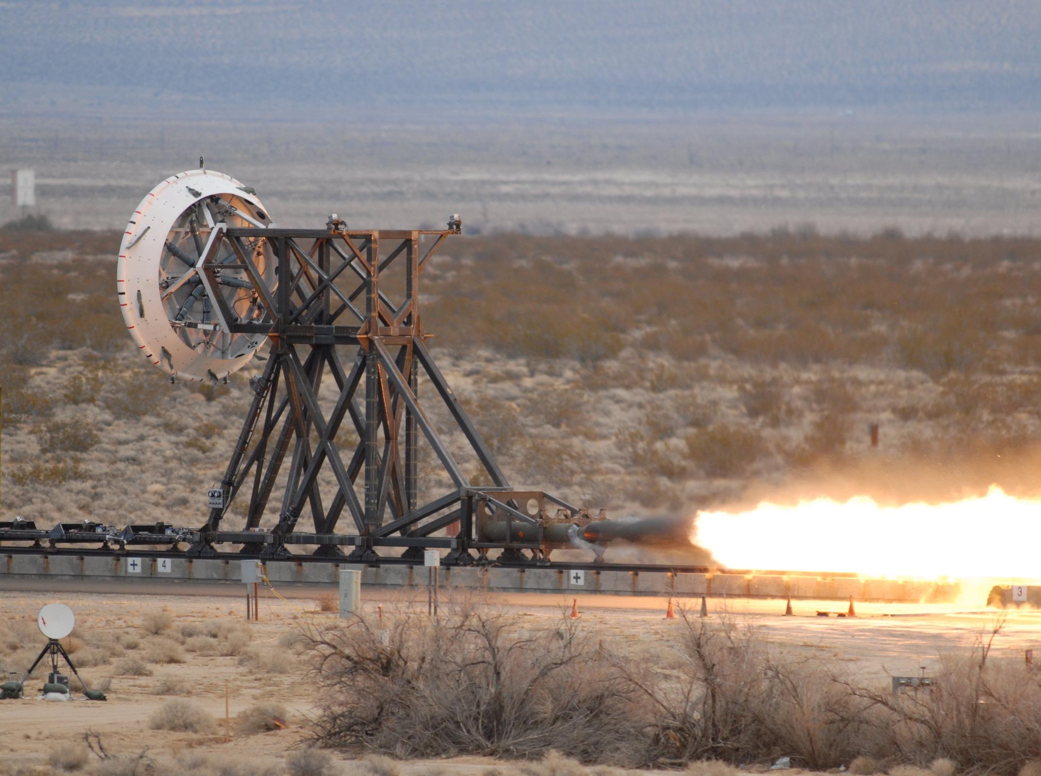 An image showing a rocket firing.  The rocket is on a train track to replicate the forces a supersonic spacecraft would experience prior to landing.