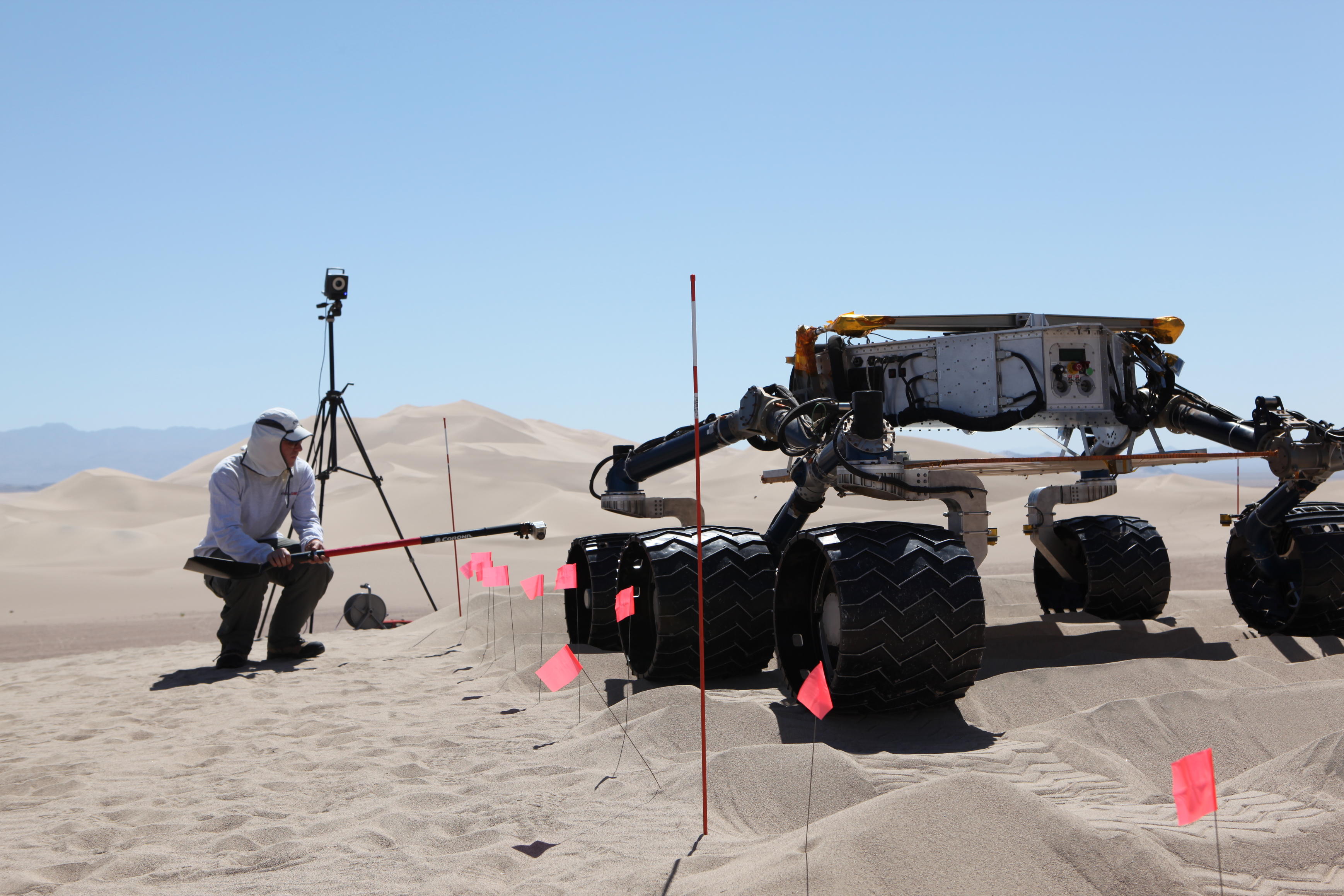 sand dune, mars rover, wheel, Dumont, Scarecrow, test - This image shows the scarecrow test rover going over a dunes obstacle course, while an engineer hunches down to see the wheels as it drives.