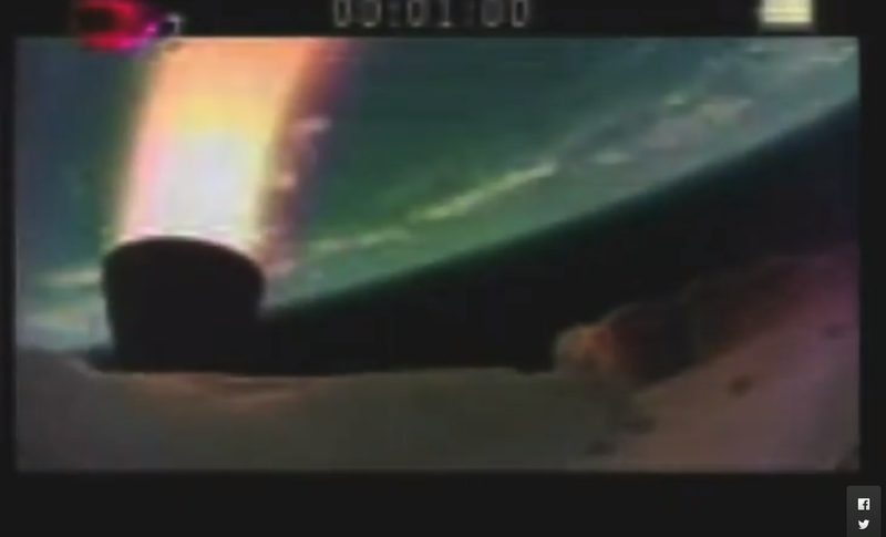 The picture show the LDSD test vehicle and an engine burn in orange/red, with Earth as a blue-green orb in the background.