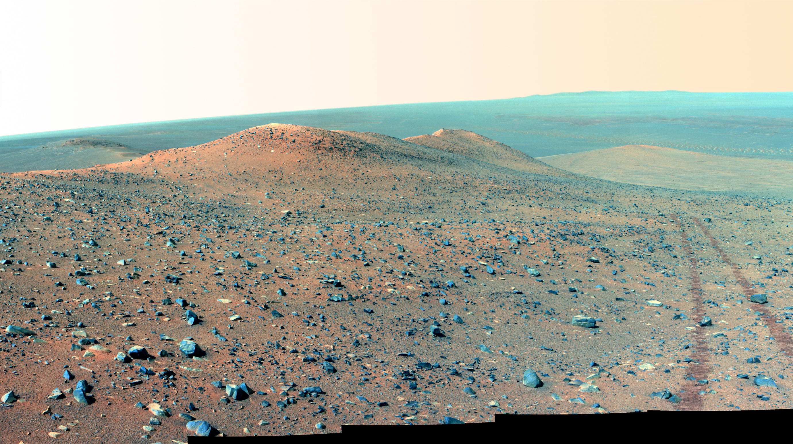 This north-looking vista from NASA's Mars Rover Opportunity shows Wdowiak Ridge, from left foreground to center. This version is presented in false color, which enhances visibility of the rover's wheel tracks at right.