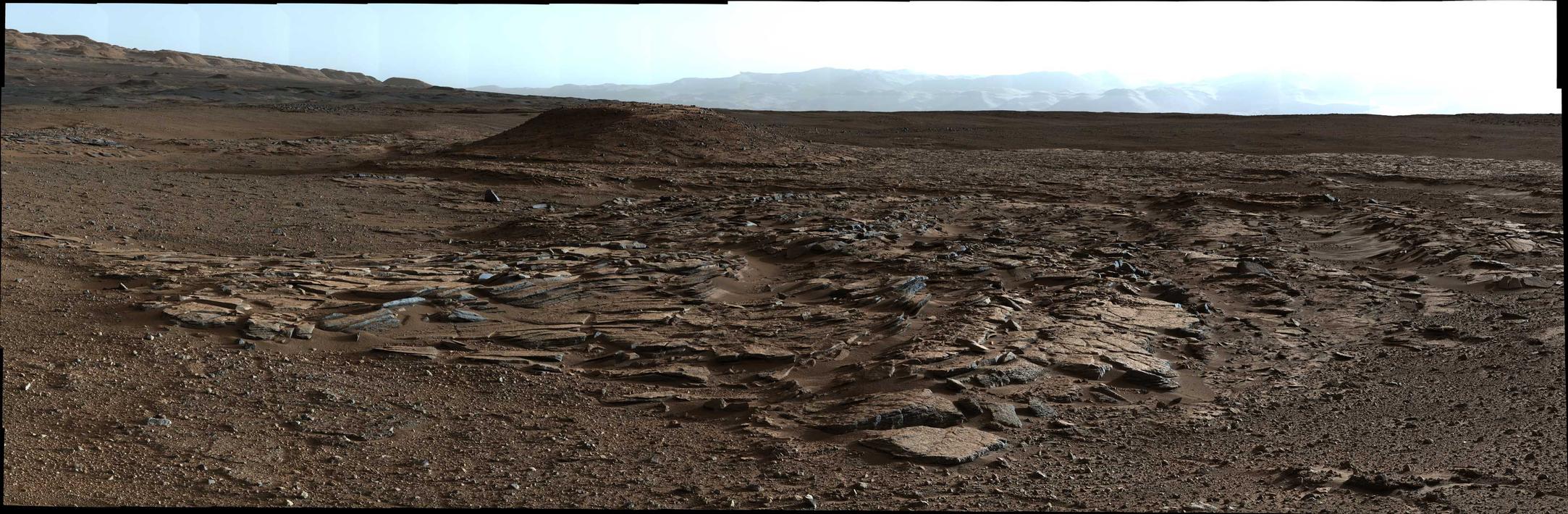 This April 4, 2014, image from Curiosity's Mastcam looks to the west of a waypoint on the rover's route to Mount Sharp. The mountain lies to the left of the scene. The image shows sets of sandstone beds inclined to the south (left), indicating progressive build-out of sediment toward Mount Sharp.