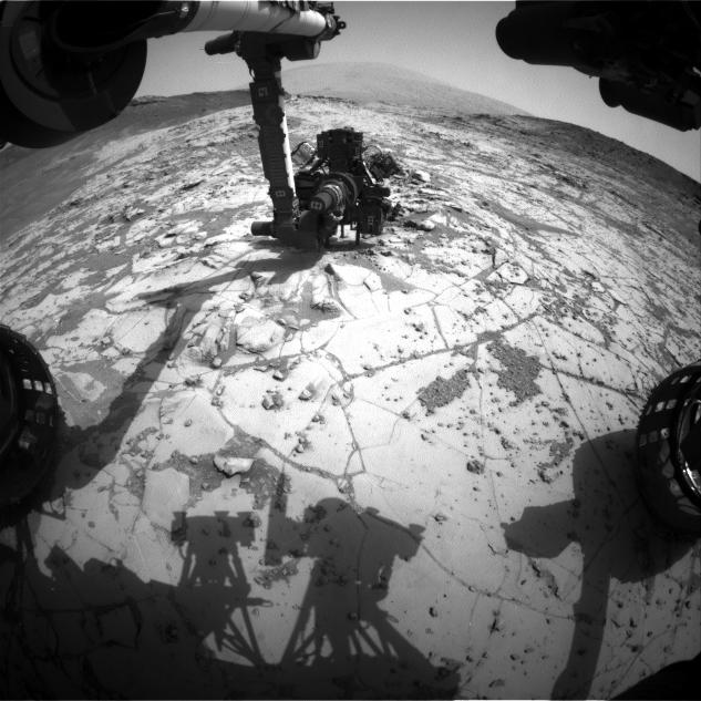 This view from the wide-angle Hazard Avoidance Camera on the front of NASA's Curiosity Mars Rover shows the rover's drill in position for a mini-drill test to assess whether a rock target called "Mojave" is appropriate for full-depth drilling to collect a sample.  It was taken on Jan. 13, 2015.