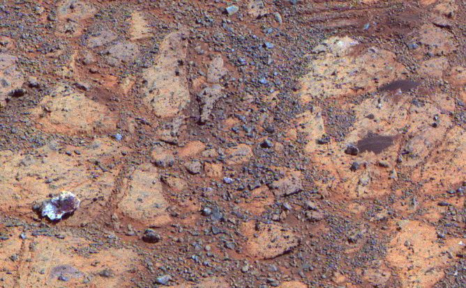 A rock with a white edge and a red center reminds us of a jelly donut in a box from the local donut shop in this image taken by Opportunity on February 4, 2014.  Named "pinnacle Island" by Opportunity's science team, this rock mysteriously appeared in an image where it had not been 4 days earlier.  Scientists believe that opportunity drove over and broke a rocks in the upper part of this image, sending that piece of pastry rolling downhill.