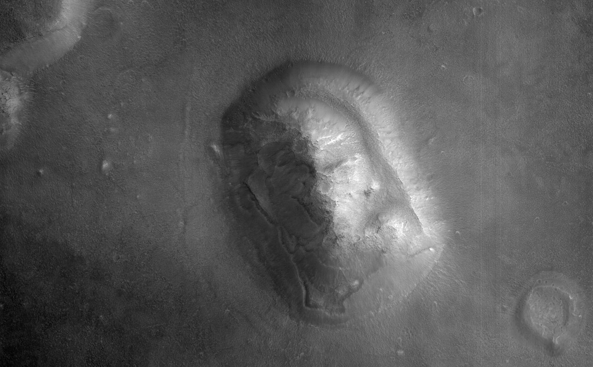 HiRISE captured this image of an eroded mesa made famous by its similarity to a human face in a Viking Orbiter image with much lower spatial resolution and a different lighting geometry.