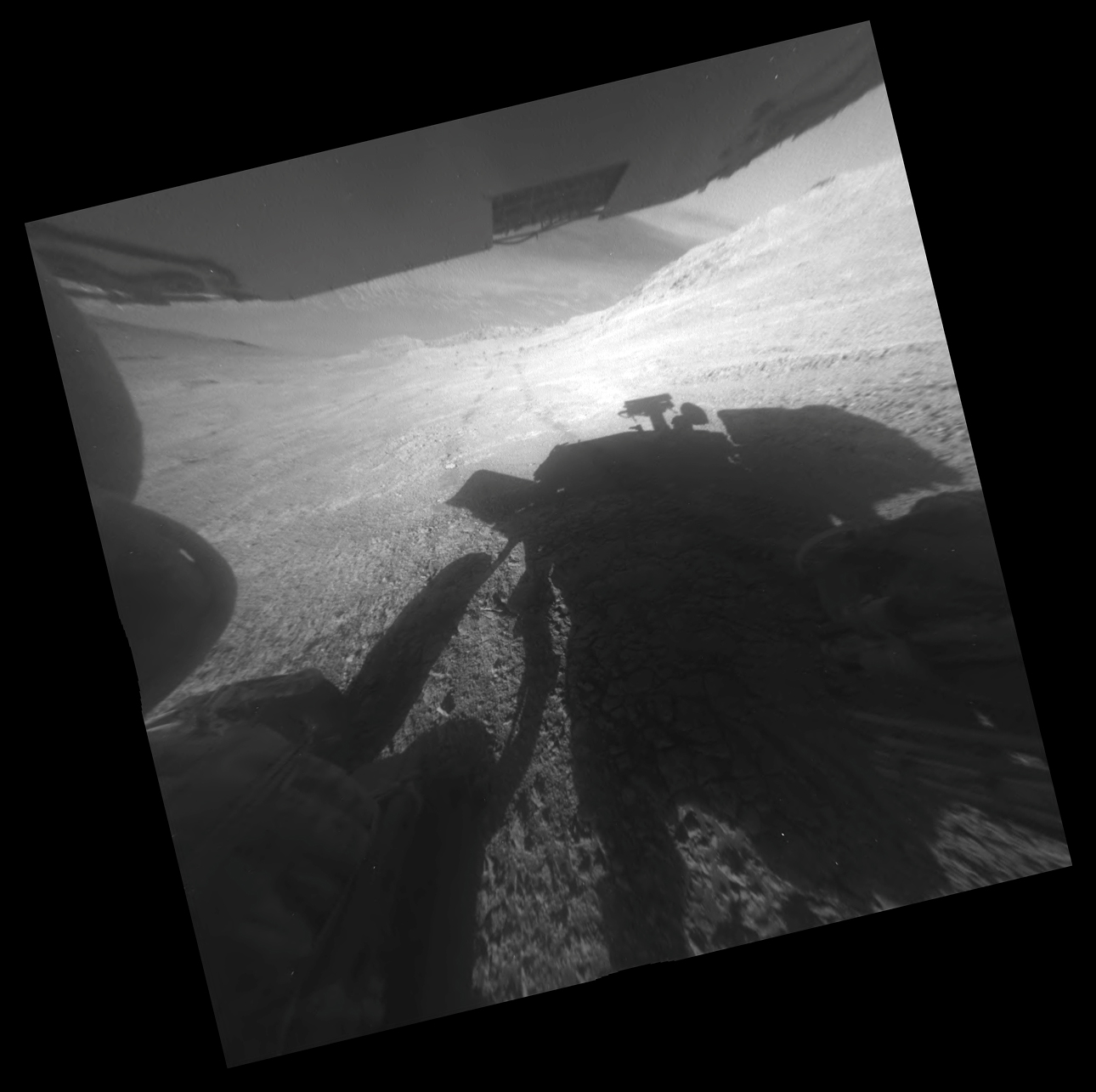 A shadow and tracks of NASA's Mars rover Opportunity appear in this March 22, 2016, image, which has been rotated 13.5 degrees to adjust for the tilt of the rover. The hillside descends to the left into 'Marathon Valley.' The floor of Endeavour Crater is seen beneath the underside of a solar panel.