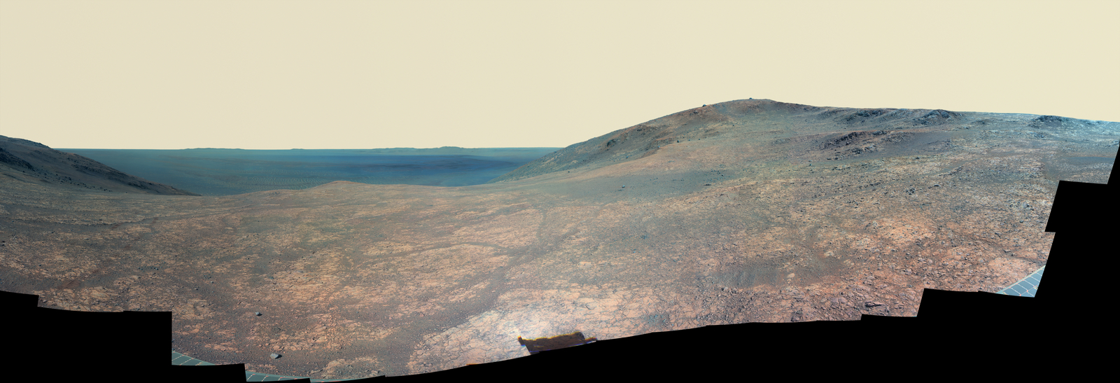 "Marathon Valley" on Mars opens to a view across Endeavour Crater in this enhanced-color version of a scene from the Pancam of NASA's Mars Exploration Rover Opportunity. The scene merges many exposures taken during April and May 2016. The foreground shows the fractured texture of the valley.