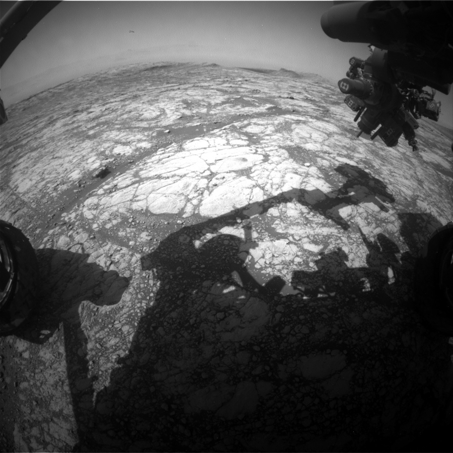 The shadow of Curiosity’s arm is visible against Mars' surface