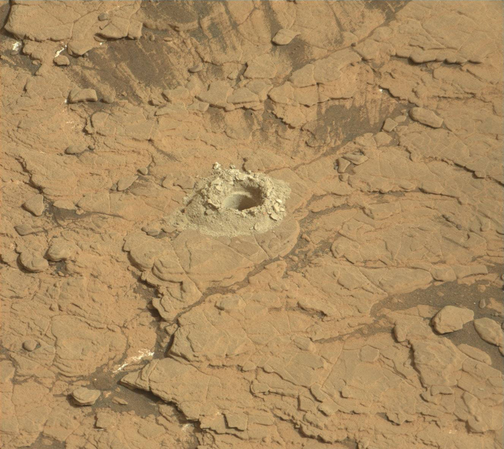 drill hole surrounded by a pile of drill tailings -
