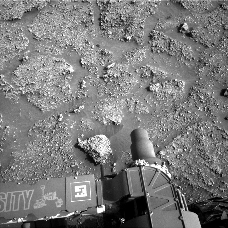 Rover image of Mars rocks with part of rover in the frame