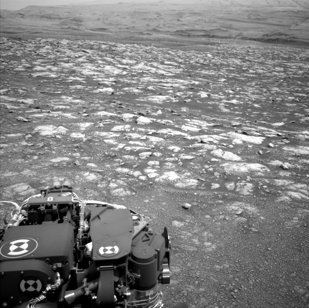 Black and white image of Mars with part of Curiosity rover showing