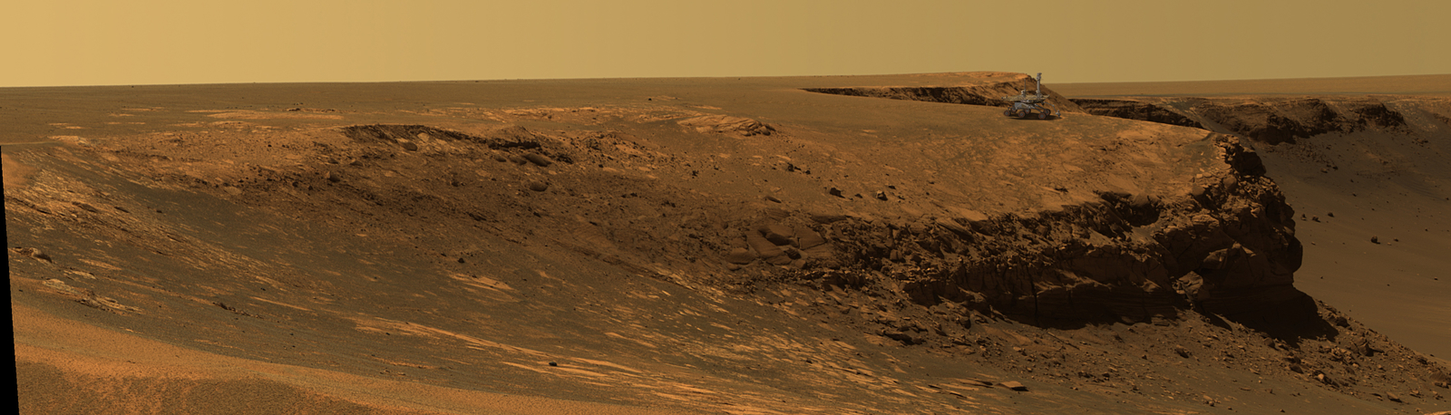This image superimposes an artist's concept of the Mars Exploration Rover Opportunity on the rim of Victoria Crater. It is done to give a sense of scale.