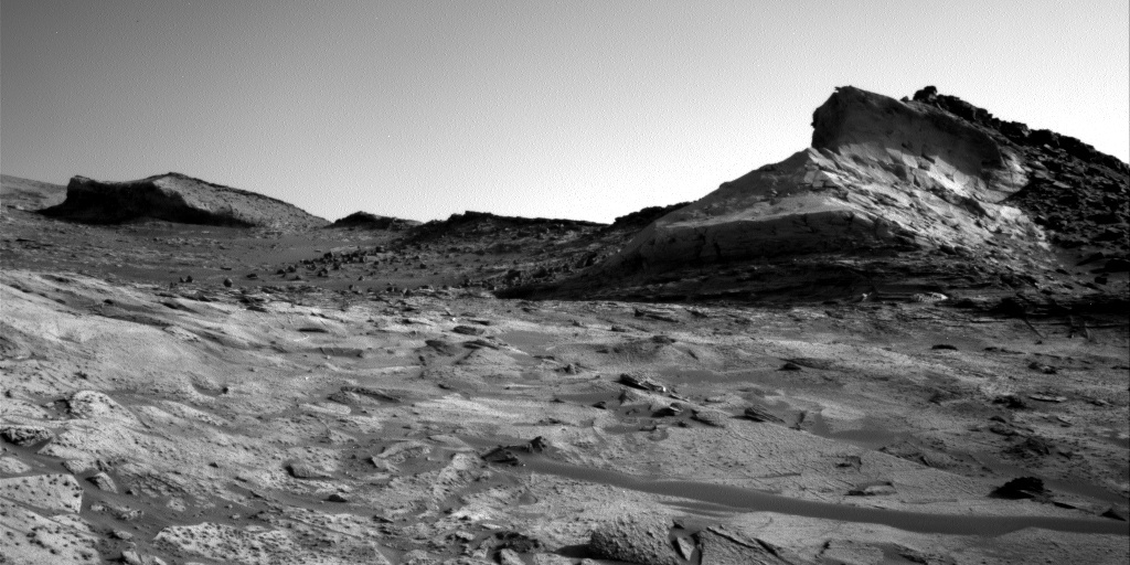 This is a black and white image of hills and miniature sand dunes. The surface of Mars is rocky.