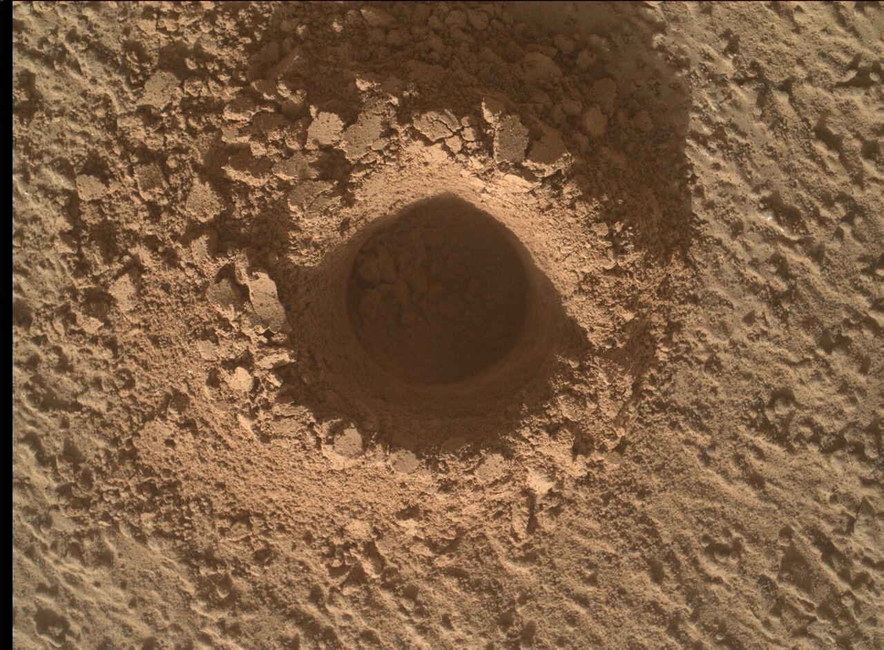 This is a close up image of a drill hole made by Curiosity. The sand surrounding and inside the drill site is crumbly and smooth.