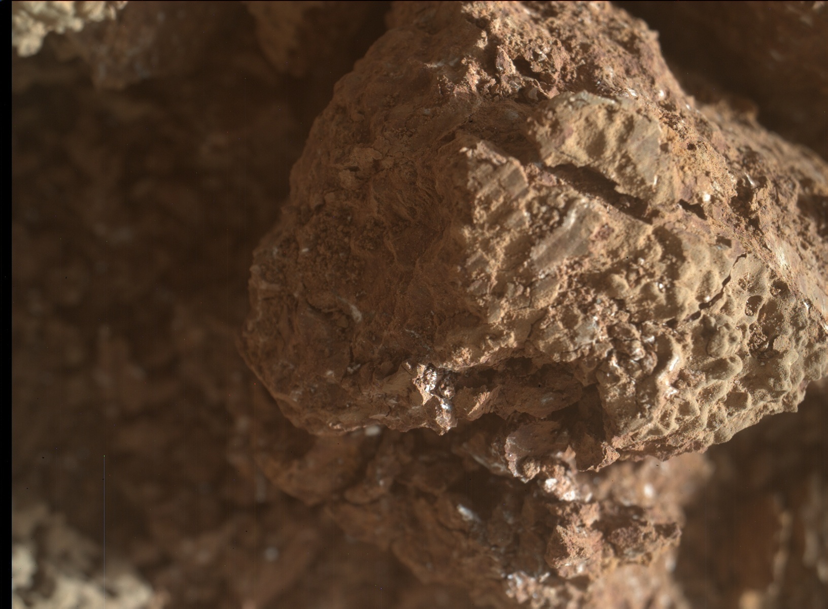 This image shows the inside of some nodules Curiosity crushed and drove over. This colored image shows a brown rock with straight imprinted lines in the middle of flattened areas that appear slightly more grey. There are also visible cracks, especially clearly on the right of the nodule in the image.