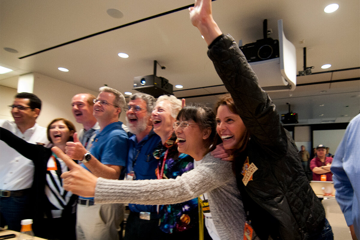 This image shows members of the Curiosity science team jump out of their seats and cheer when they hear that the Curiosity rover has successfully landed on the Martian surface.