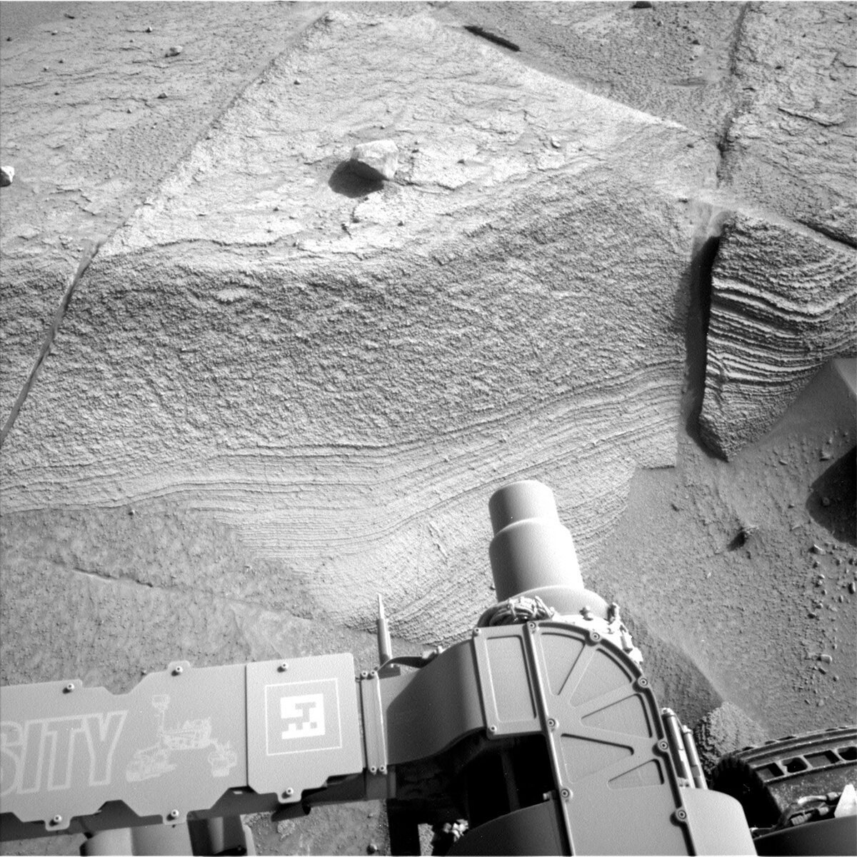 This image shows part of the Curiosity rover standing before rock on the Martian surface on sol 3771.
