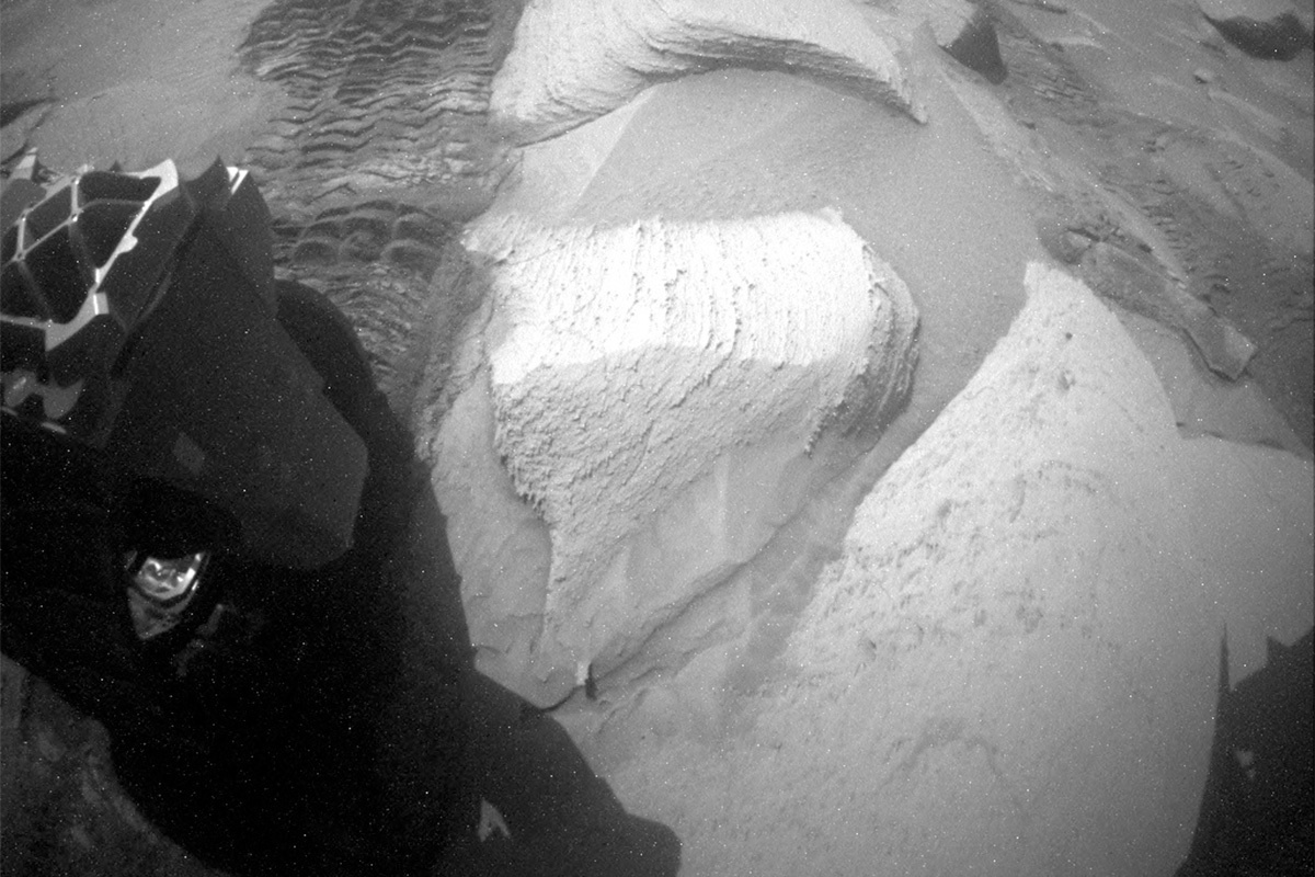 This image showing large rock formations and part of the Curiosity rover on Mars was taken by the Curiosity rover's Rear Hazcam on Sol 3796.