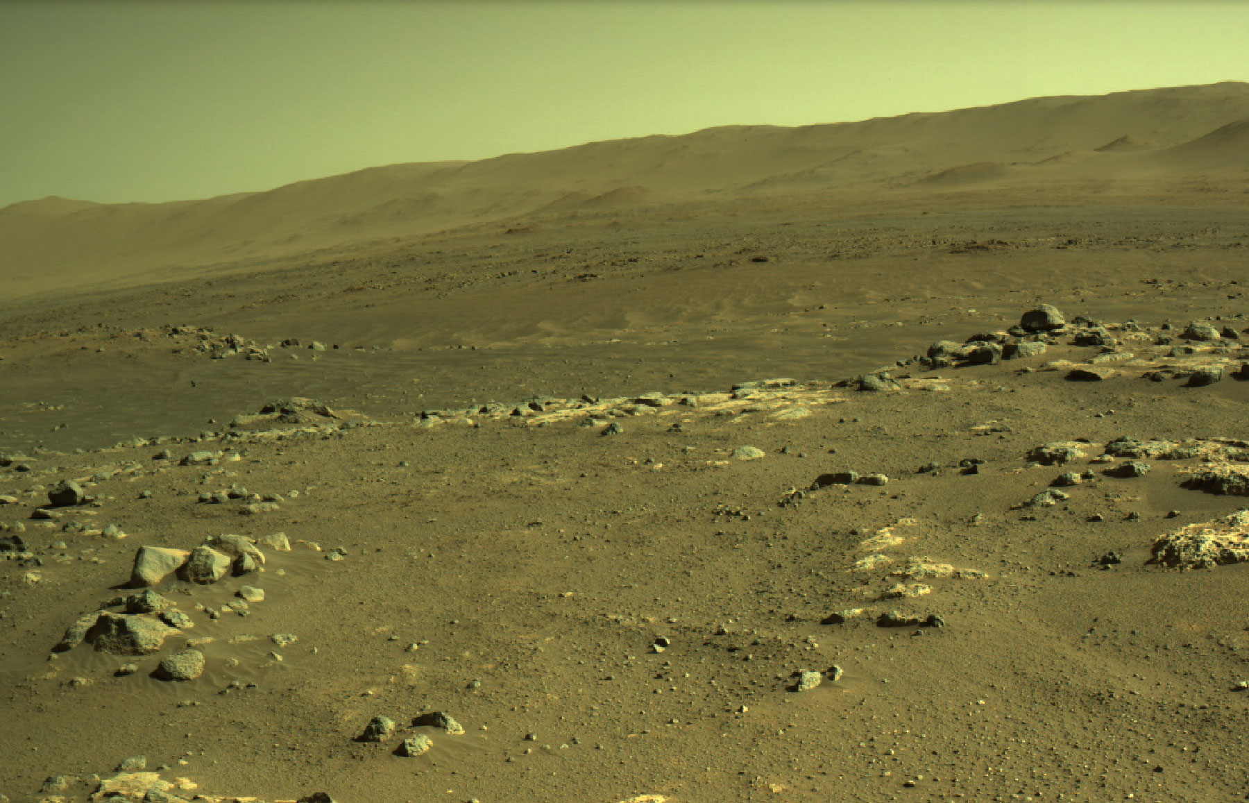 Perseverance rover took this image overlooking the sandy “Séítah” region. The Ingenuity helicopter flew over this region during its ninth flight and it shows the rocky surface of mars and hills in the background.