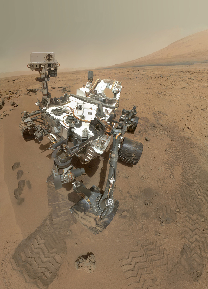 A Mars rover is parked among the tire tracks it made on Mars in this composite image.