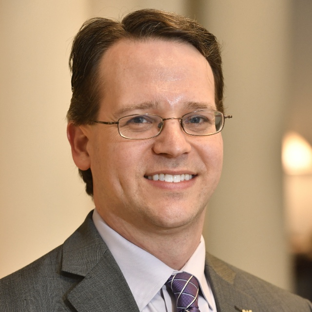 Headshot of a smiling man wearing glasses.