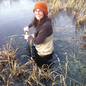 Photo of a woman standing waist deep in marshy water.