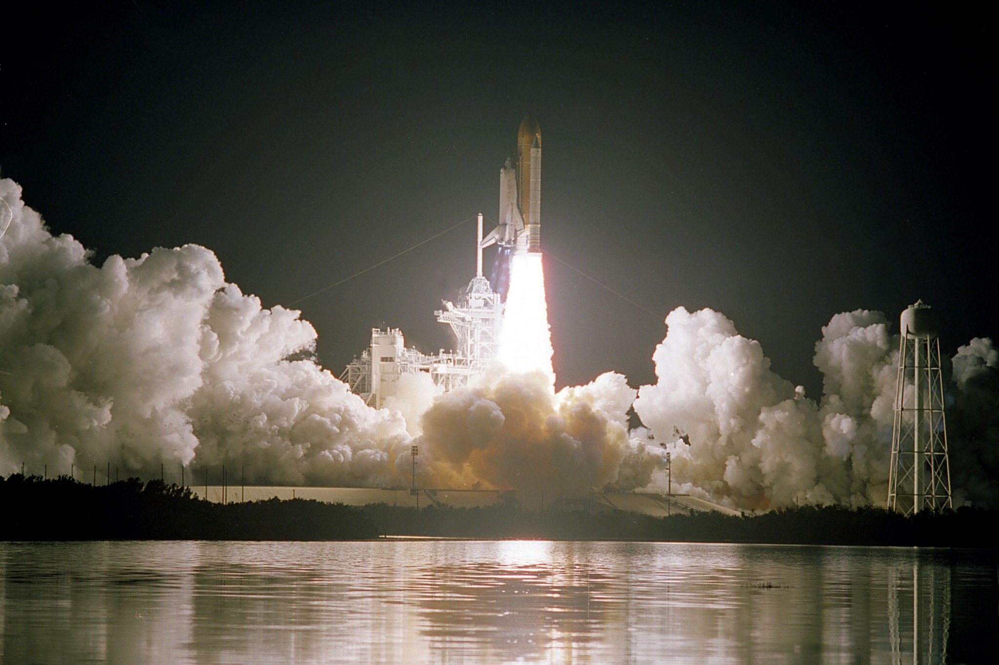 The Space Shuttle Discovery launches among billowing smoke and flame from the engines at Kennedy Space Center.