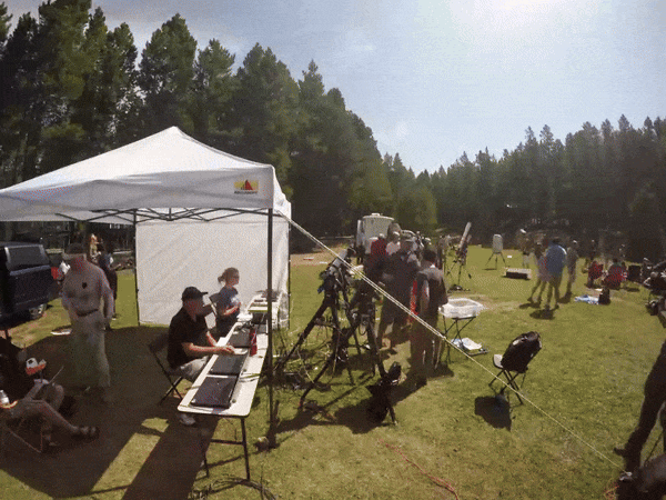 A GIF showing a timelapse of people moving around during an eclipse during a bright day. It briefly gets much darker, then lighter again.