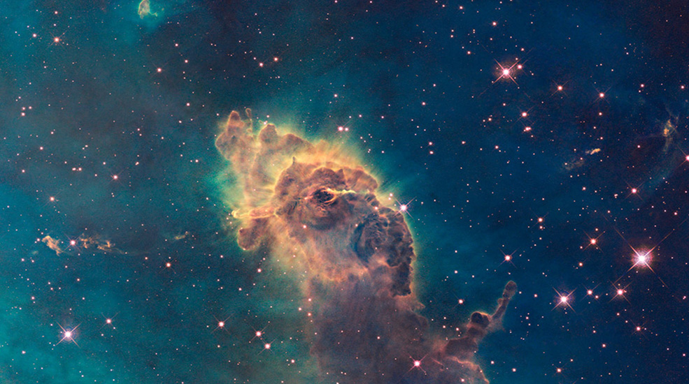 Entire image is filled with green, brown, rusty colors of the Carina Nebula. Chaotic groupings of this dust and gas with stars dispersed randomly throughout the image.
