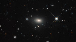 Black space with multiple galaxies visible, large white glowing supermassive black hole in the center and two bright stars on each side.